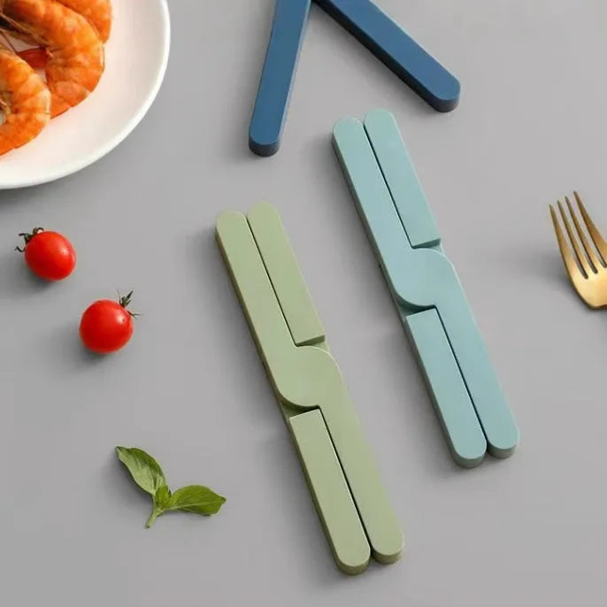 Green and teal folding silicone pot mats on a gray surface with tomatoes and a fork