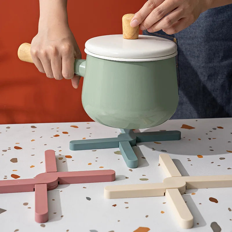 Cross-shaped silicone pot mats under a pot on a set table