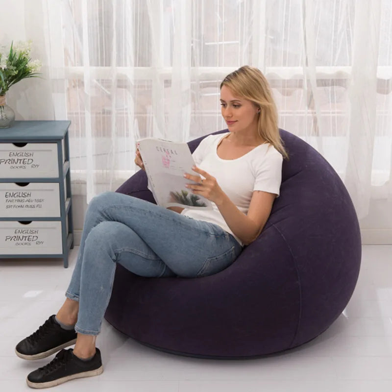 Woman reading on a dark blue inflatable lazy sofa in a bright living room