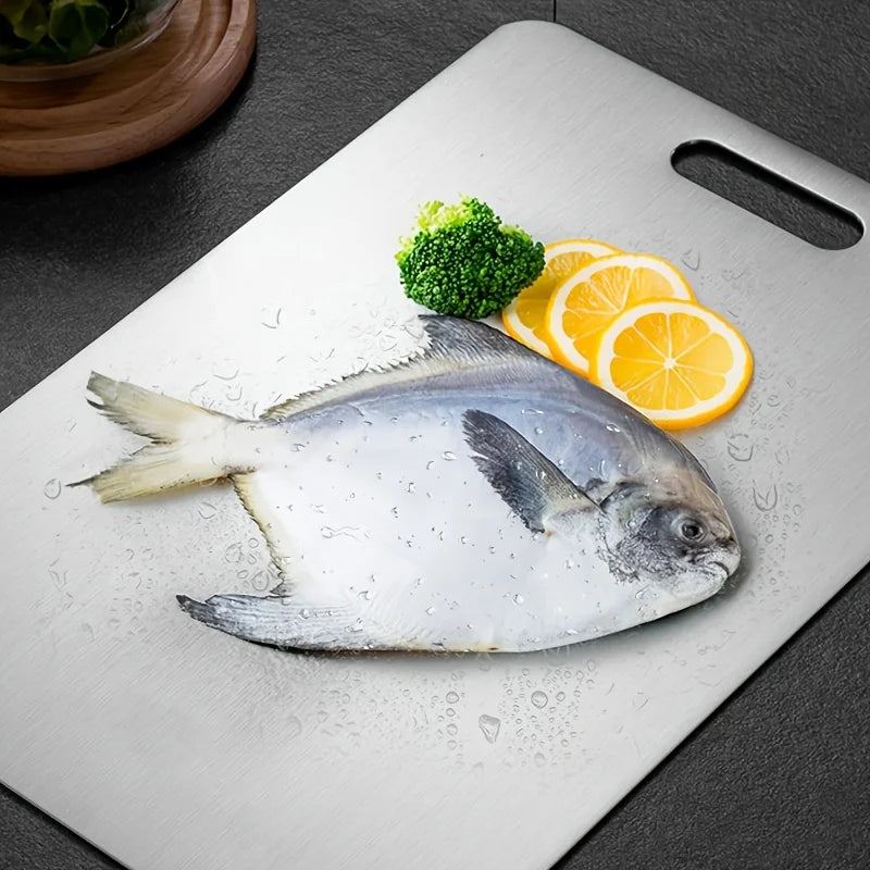 Stainless steel cutting board with a whole fish and lemon slices