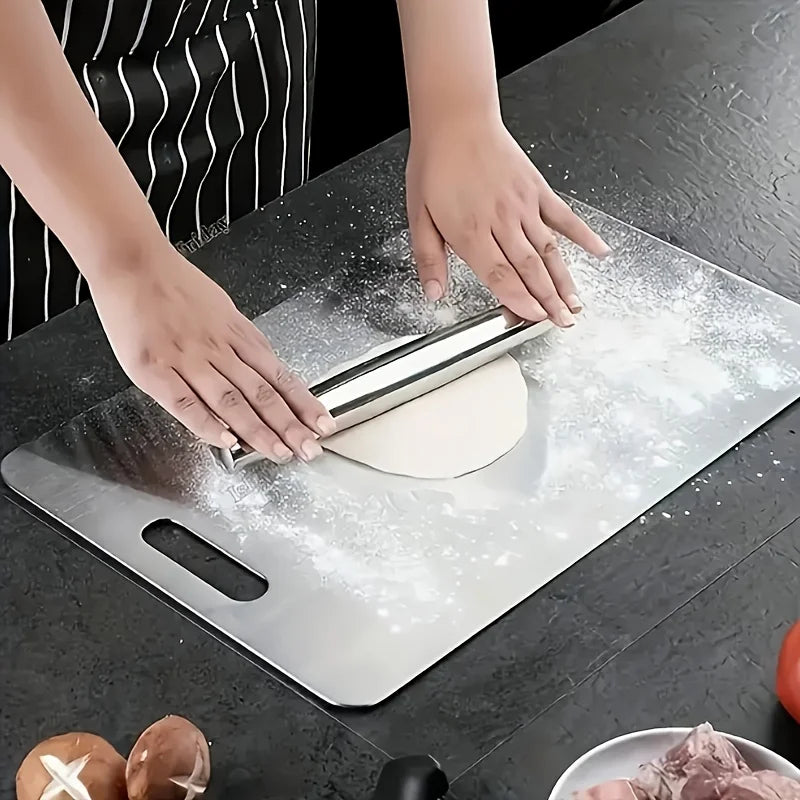 Hands rolling dough on a stainless steel cutting board