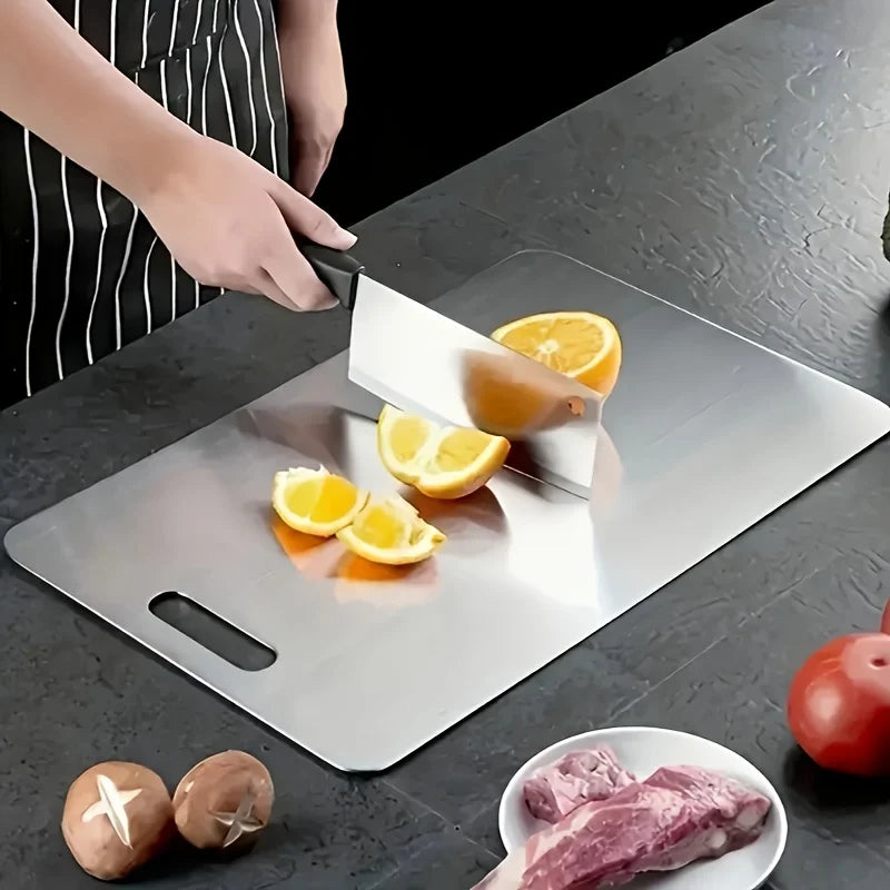 Stainless steel cutting board with sliced lemon, tomatoes and meat